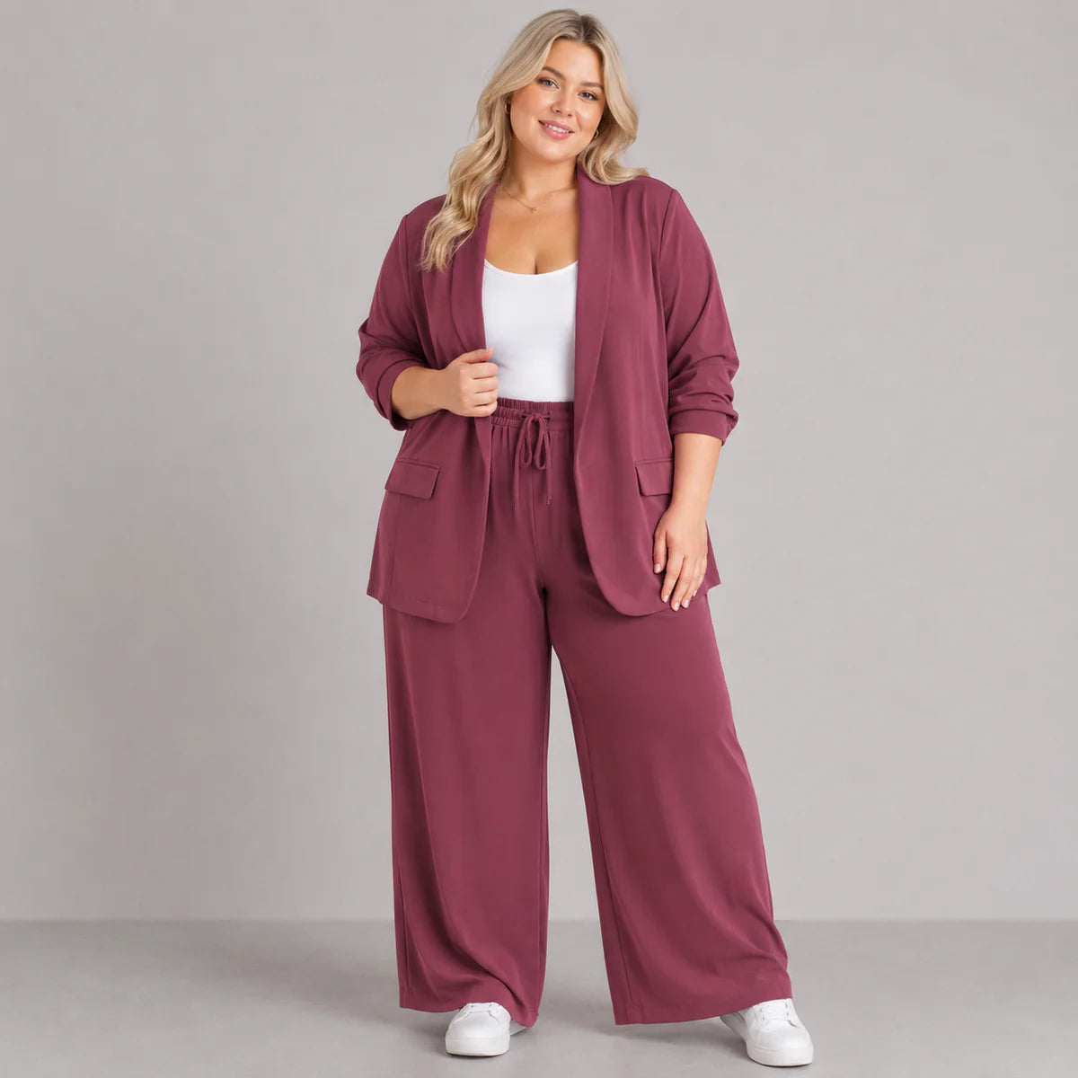 Woman wearing a maroon tracksuit with a white top on a gray background